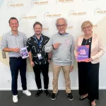 Auf dem Bild sind vier Menschen im Landtag in München zu sehen. Sie stehen vor einer weißen Wand mit dem Logo der Freie Wähler darauf. Sie halten Broschüren in der Hand. Zwei Menschen sind Politiker der Freien Wähler, Julian Preidl und Gabi Schmidt. Die anderen beiden sind Andreas Jäger und Bernd Strieder vom VPBy.